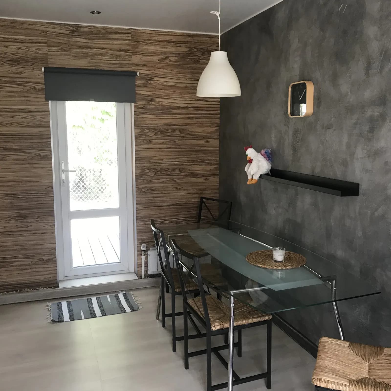 Dining corner with a glass table, black metal chairs, and a white pendant lamp